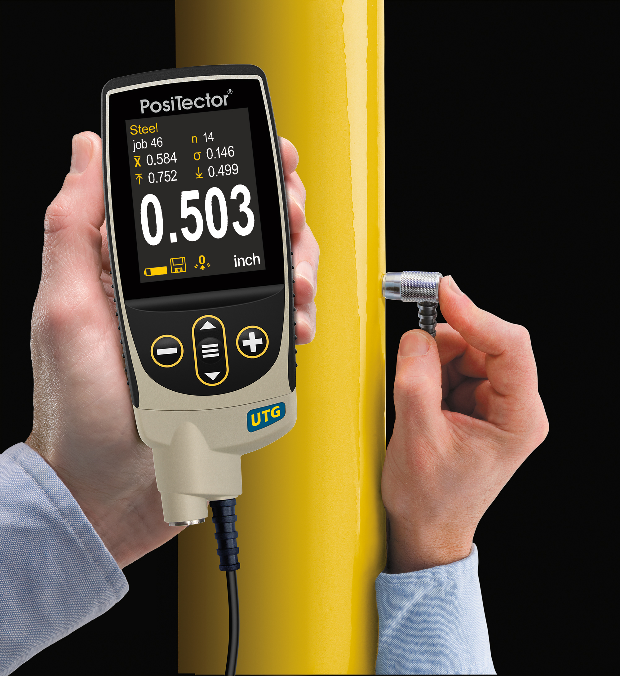 An operator holds a PosiTector UTG while its probe touches a yellow painted steel pipe.